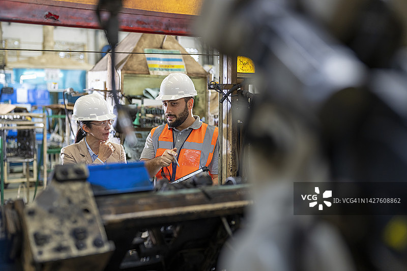 工程师与经理讨论工厂机器人手臂焊接单元的工作计划图片素材