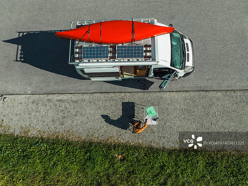 女子在露营车旁烹饪的航拍，配有红色船只图片素材