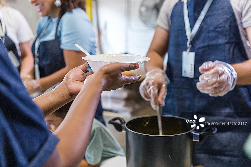 在食物银行活动上手捧一碗汤的女士（未识别）图片素材