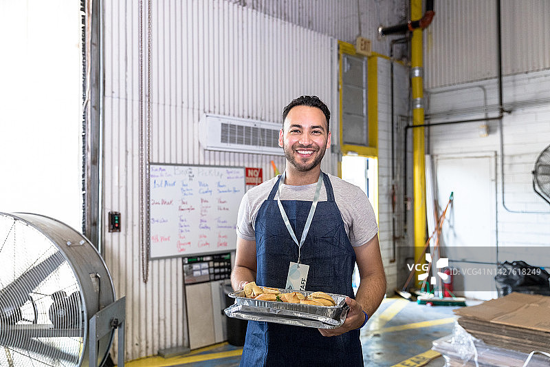 在食物银行活动中，年轻男人拿着一盘三明治图片素材