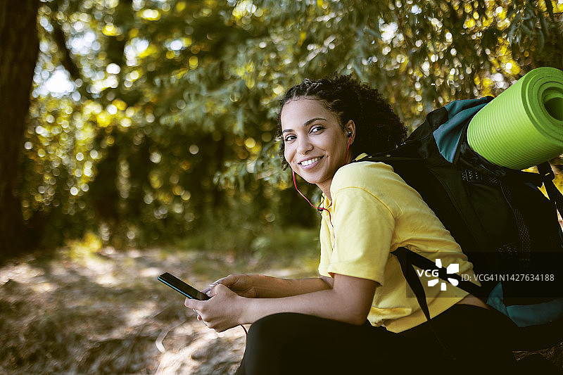 年轻女人在森林里使用智能手机图片素材