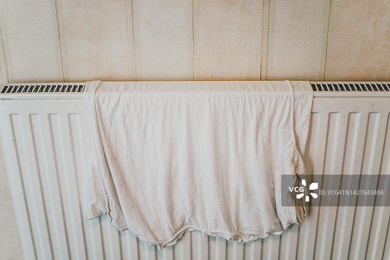 在家用电暖气上晾晒的白色衣服图片素材