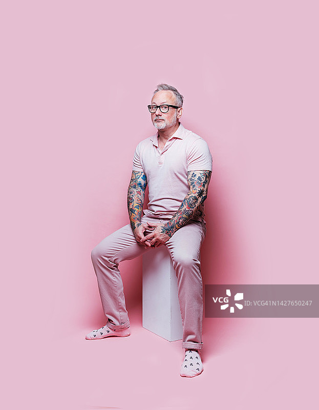 穿粉色衣服站在粉色背景上的休闲男人图片素材