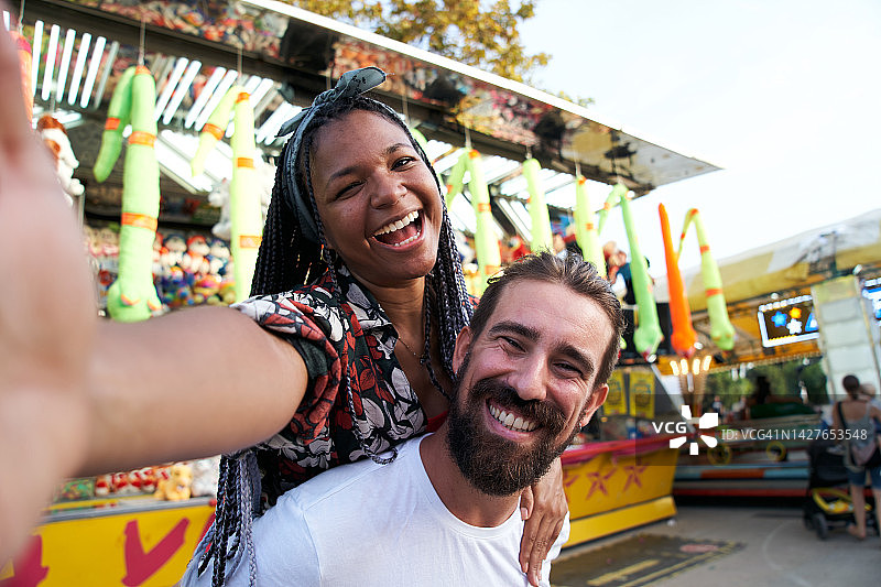在游乐园里玩得开心的快乐有趣的混血夫妇图片素材