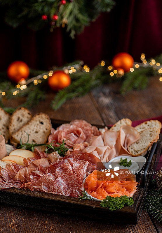 含火腿、萨拉米香肠、三文鱼和面包的开胃菜拼盘，用于乡村厨房的圣诞庆祝活动图片素材