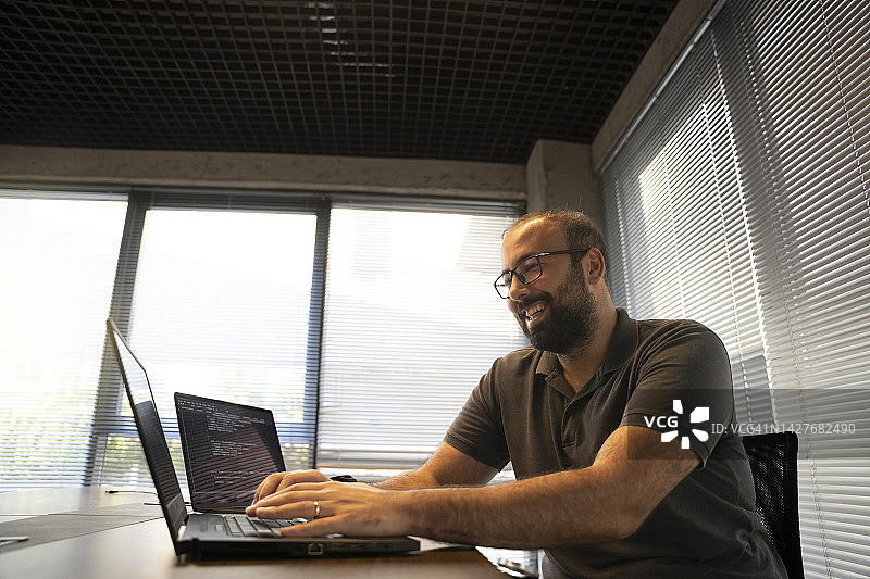 快乐的程序员在笔记本电脑上编写代码图片素材