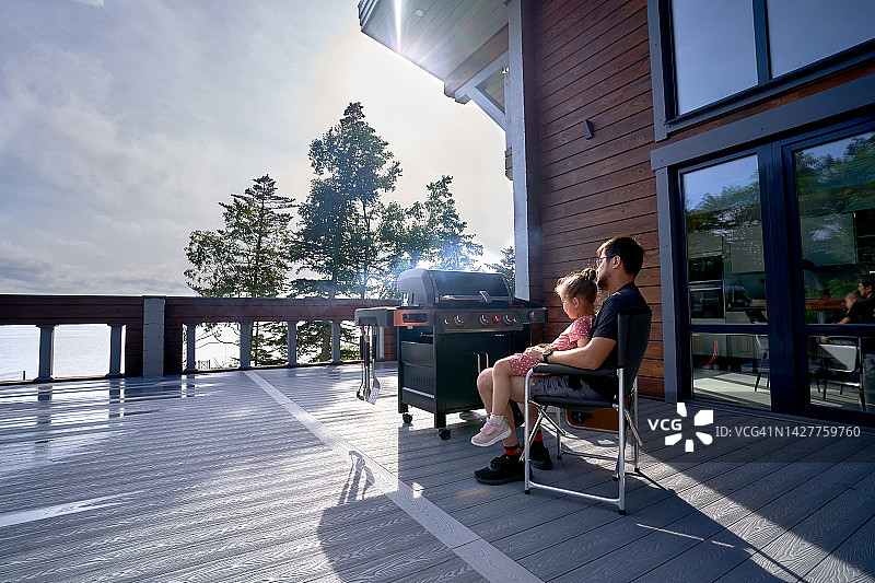 韩国男人和女儿在阳光明媚的露台上烤肉图片素材