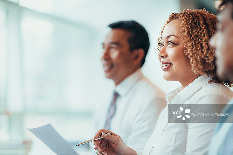 日本非裔美国成熟女商人学生在商务办公室教室里与多民族同事一起参加教育培训研讨会，坐着倾听、微笑、学习图片素材