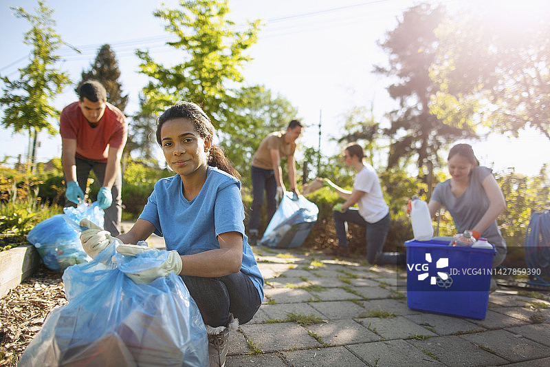 西班牙裔女学生在社区公园帮助清理和回收纸张和塑料瓶的肖像，多元种族青年组织夏季志愿者慈善活动图片素材
