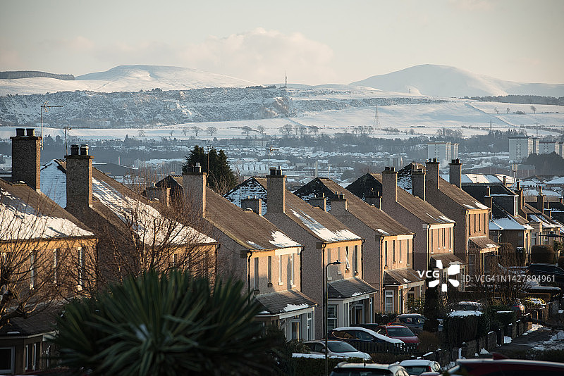 苏格兰爱丁堡冬日里一排部分被雪覆盖的房屋，背景是彭特兰山图片素材