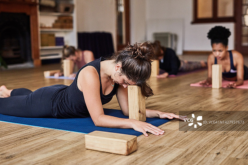 禅意工作室，女性使用瑜伽砖伸展身体，进行普拉提课程图片素材