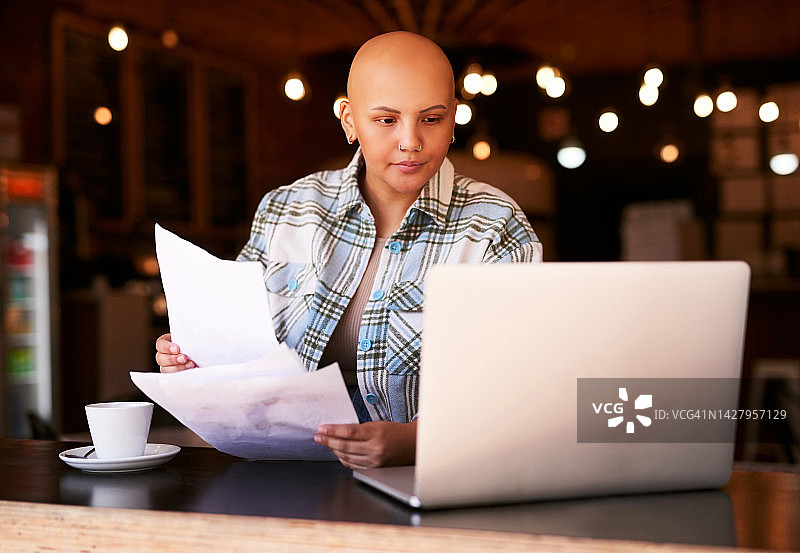 咖啡馆，女人在线进行自由职业工作，患有癌症幸存者证明。 斑秃，脱发或化疗的希望。 咖啡店里有医疗账单，保险合同或结果的光头女士图片素材