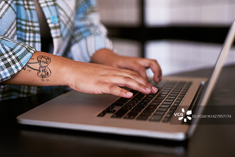 有纹身的手在笔记本电脑上打字，一位有创意的员工或艺术家在线工作。技术、沟通和网页设计，在创业公司工作的女性通过网络进行数字营销图片素材
