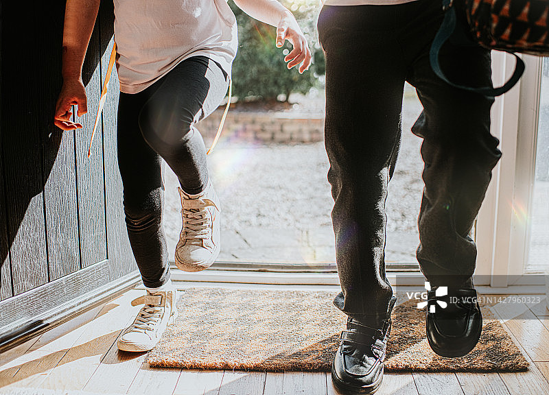 放学后穿着校服进入家门的两个孩子图片素材