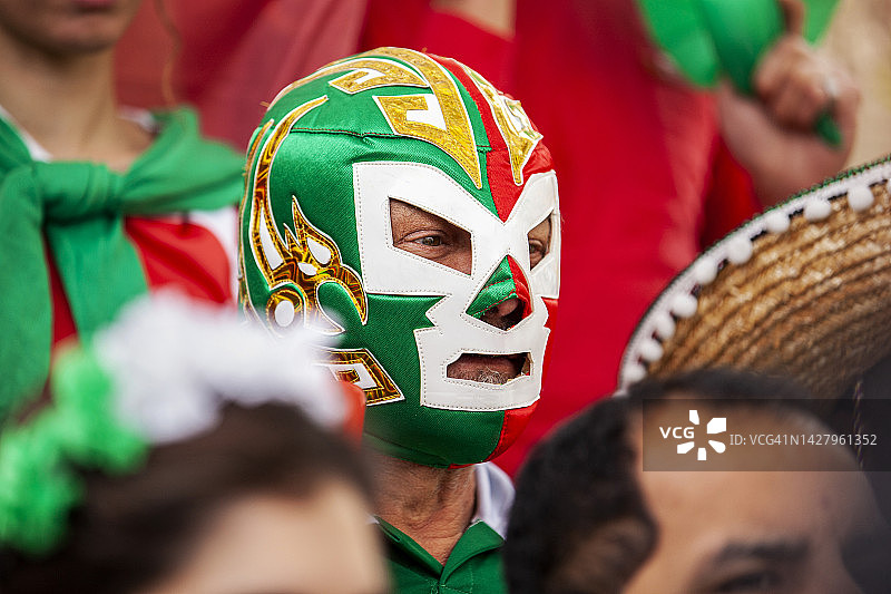 专心致志的墨西哥足球迷戴着摔跤面具在体育场观看比赛图片素材