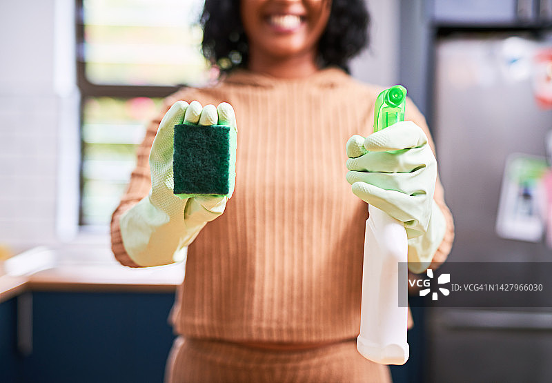 清洁、房屋与卫生：女性在厨房进行春季大扫除，手持清洁产品、喷雾瓶和海绵。家庭主妇为清洁的家感到自豪图片素材