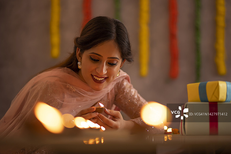 排灯节期间，女人在桌子上摆放油灯装饰办公室图片素材