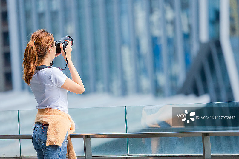 在城市中使用相机拍照的亚洲女人图片素材