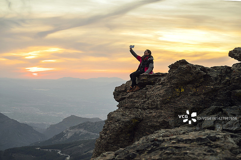 在日落时分在山上自拍的女人图片素材