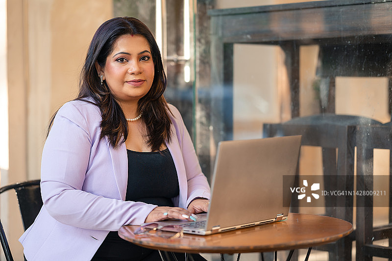 在咖啡店使用笔记本电脑的印度妇女图片素材
