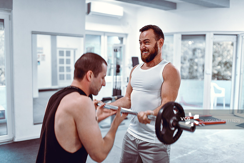 留着胡须的男人正在努力进行杠铃弯举运动图片素材