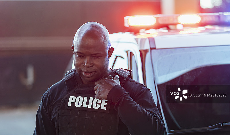 表情严肃的非裔美国警察，警灯闪烁图片素材