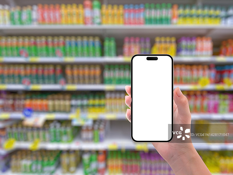 在超市过道上手持白色空白屏幕的智能手机图片素材