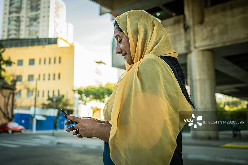 戴着头巾的黎巴嫩妇女在街上使用手机图片素材