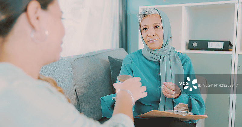 在沙发上与穆斯林心理医生咨询的女人，手中拿着精神健康或保健药物。在治疗师或办公室的沙发上，医生讨论药物以及药丸如何帮助患者图片素材