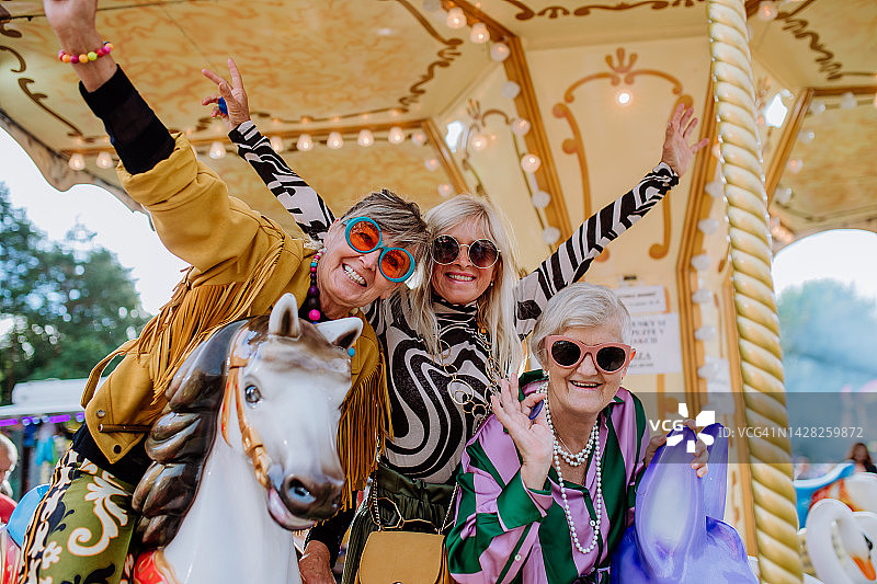 在旋转木马上享受乡村集市的快乐老年朋友图片素材