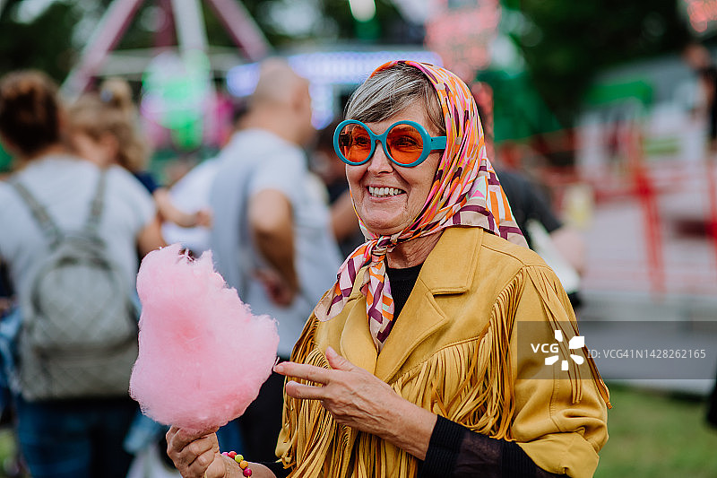 快乐的老年妇女享受乡村集市，吃棉花糖图片素材