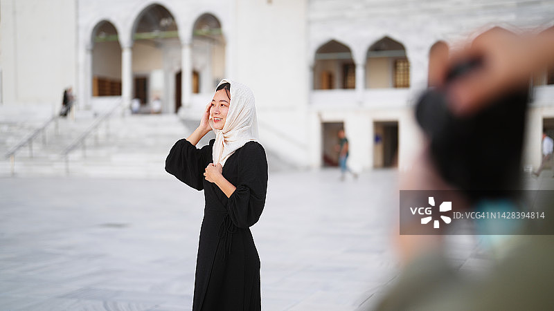 年轻女游客和社交媒体网红在旅行期间参观清真寺时被拍摄图片素材
