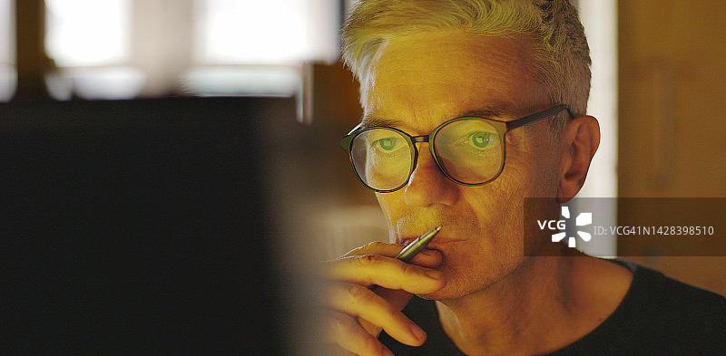 年长的男人专注地看着屏幕图片素材