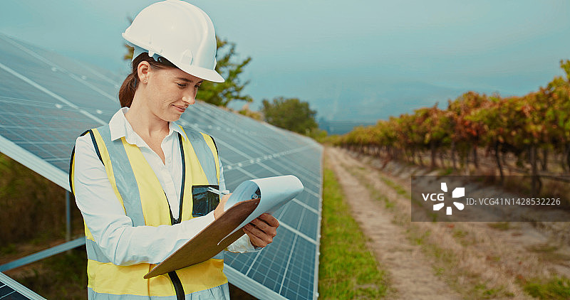 从事太阳能发电场或在纸上书写的工程女性，关于电力、可持续性电网或可生物降解的太阳能发电场。思考可再生能源领域中的维护工人，以实现未来的生态电力图片素材