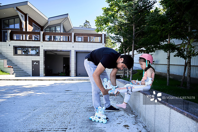父亲帮助女儿脱掉旱冰鞋图片素材