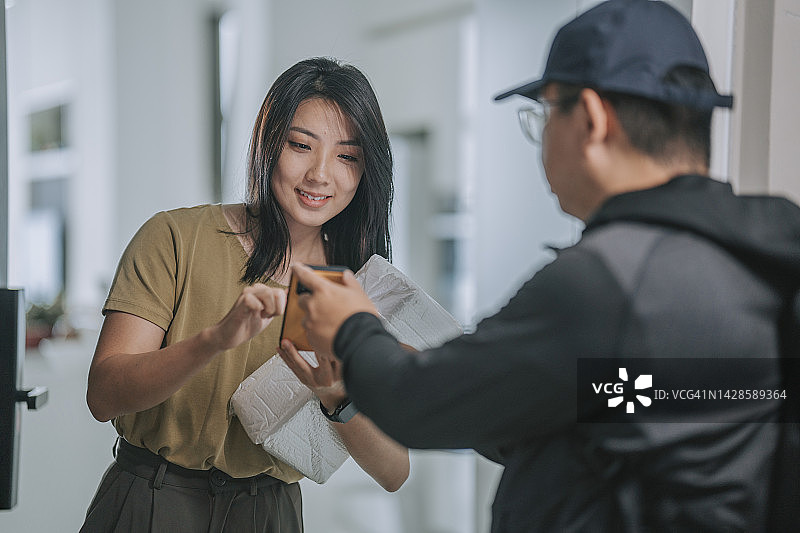中国亚洲女性签收智能手机送货包裹图片素材