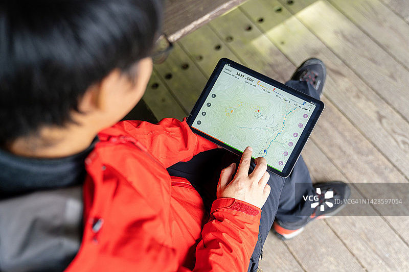 徒步旅行时，男子在平板电脑上看地图图片素材