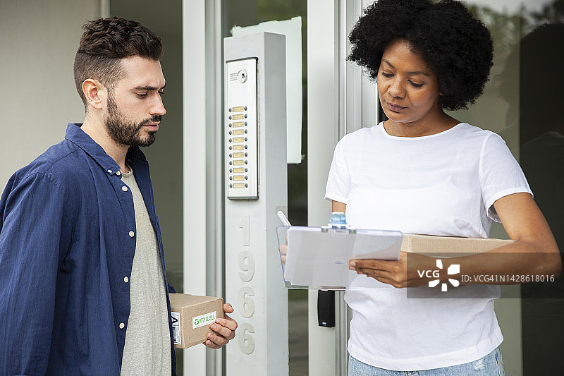 非裔美国妇女在收到送货员的包裹后签署表格图片素材