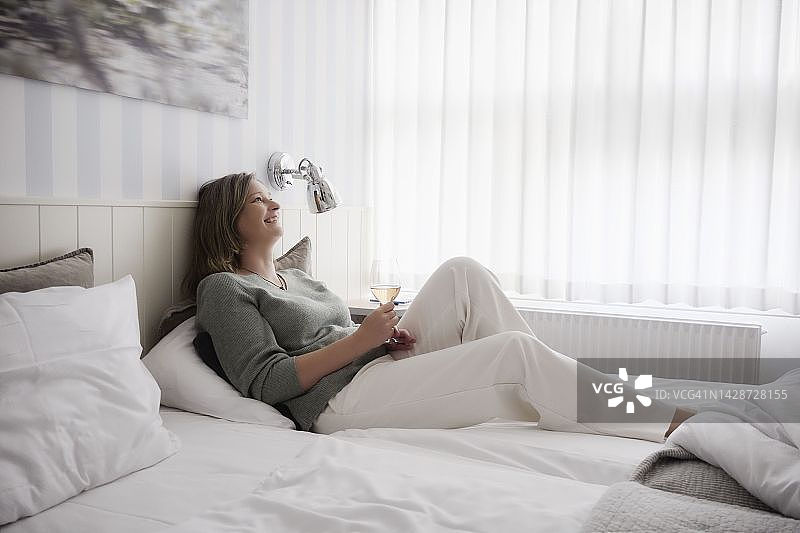 床上喝玫瑰红酒的模特图片素材