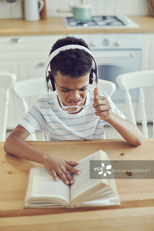 戴眼镜的小非洲男孩看书吃力图片素材