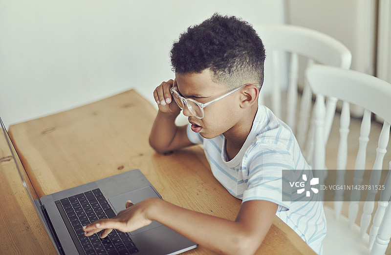戴眼镜的非洲小学生看笔记本电脑屏幕图片素材