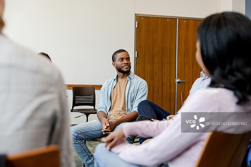 小组治疗中，年轻男人倾听咨询师的建议图片素材