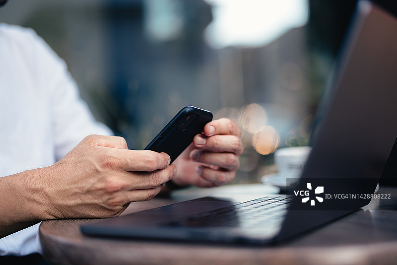 在咖啡馆使用手机和笔记本电脑的匿名商人图片素材