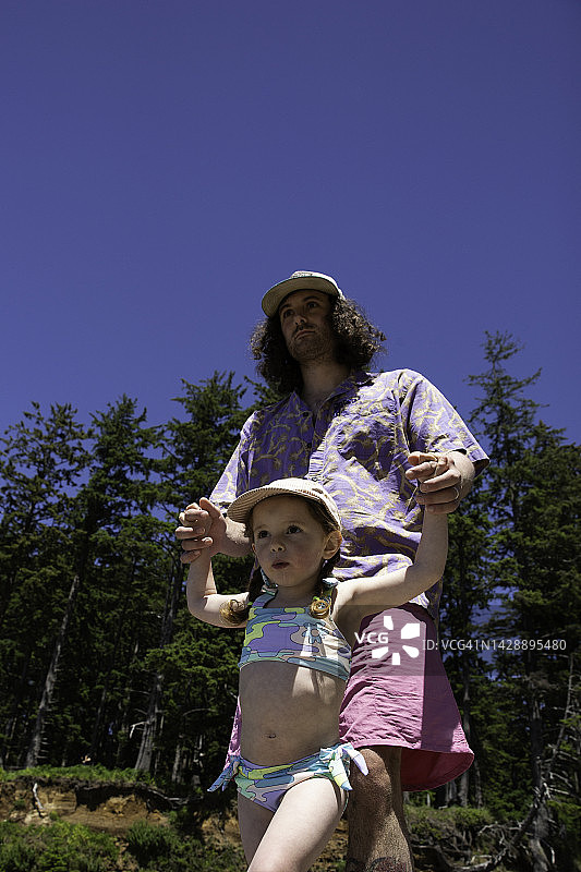 夏天海滩上父亲沿着树行走的仰视角度图片素材