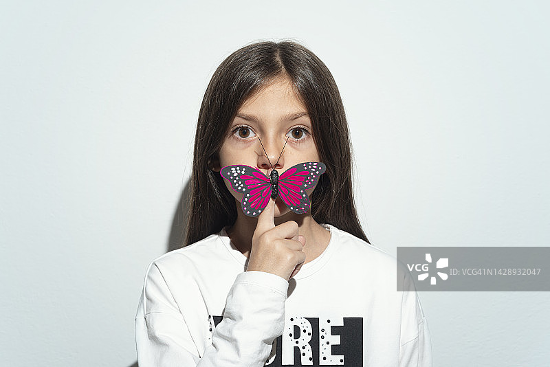 带着蝴蝶、手指放在嘴唇上的小女孩图片素材