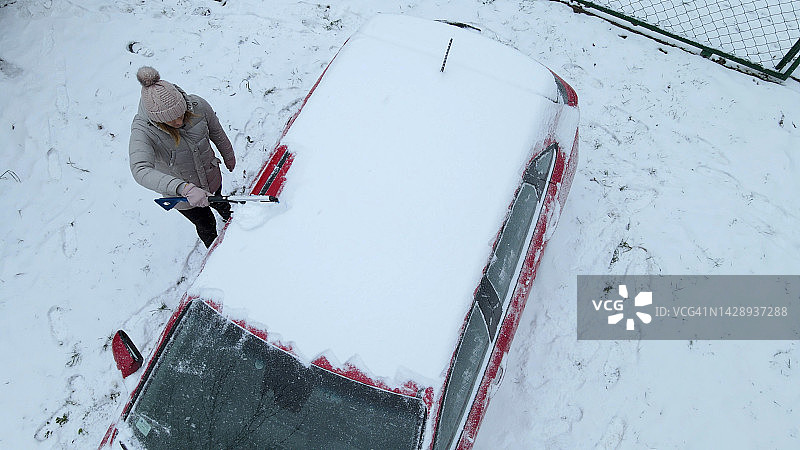 女子清理汽车积雪鸟瞰图片素材