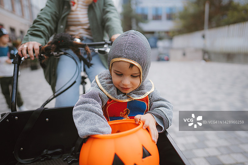 骑着货运自行车进行万圣节寻宝的小男孩图片素材