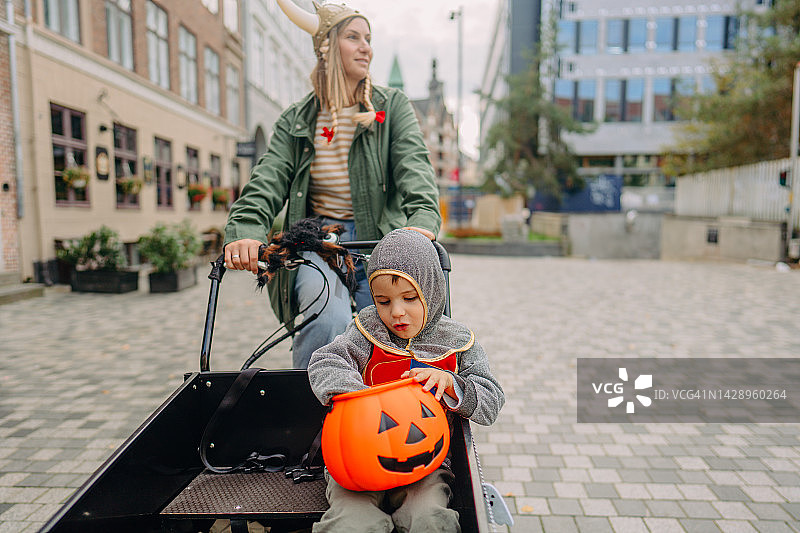 骑着货运自行车进行万圣节寻宝的小男孩图片素材