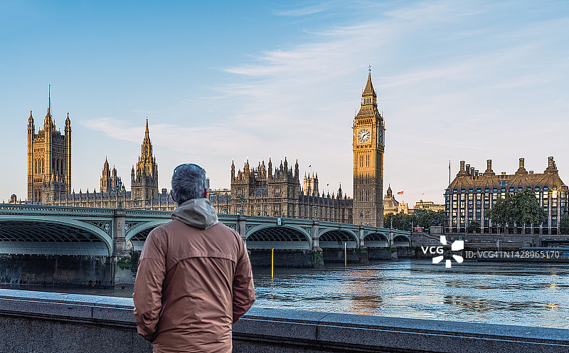 日出时分，男人看着伦敦的大本钟和威斯敏斯特桥图片素材