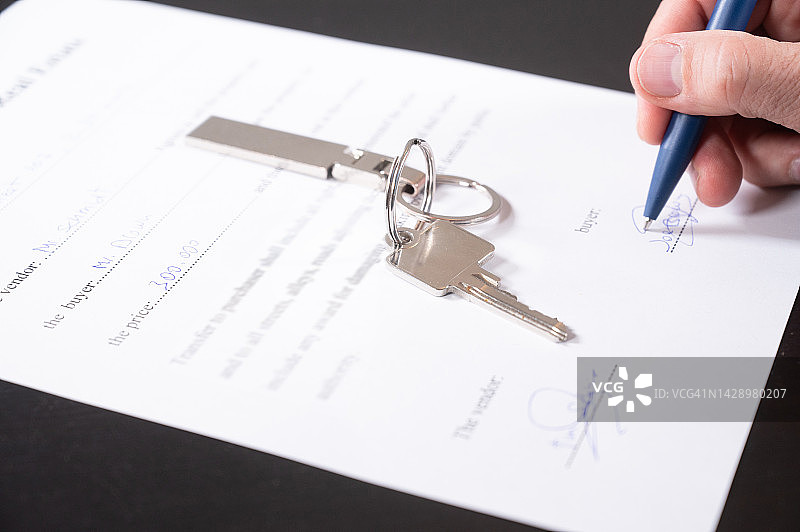 房屋买卖概念：买家签署购房合同桌上有钥匙图片素材
